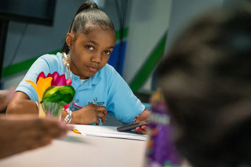 Kayleigh, a young girl, doing her homework looking at a camera